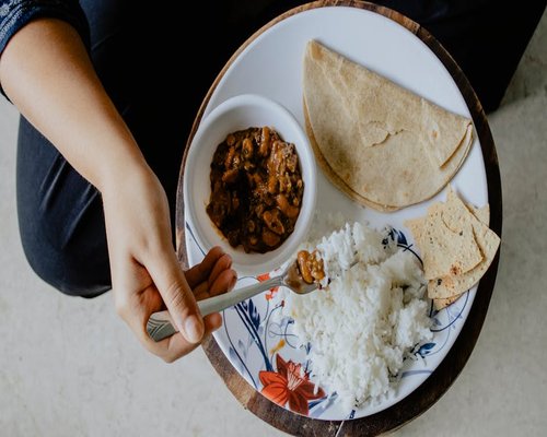 A clean plate with Indian roti, sabzi, and dal setting on a table with natural light